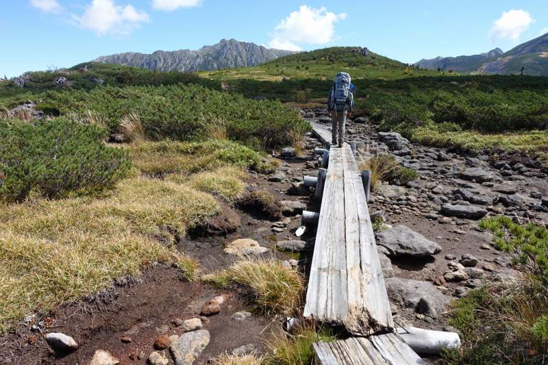 1055_水晶岳をバックに歩く登山者